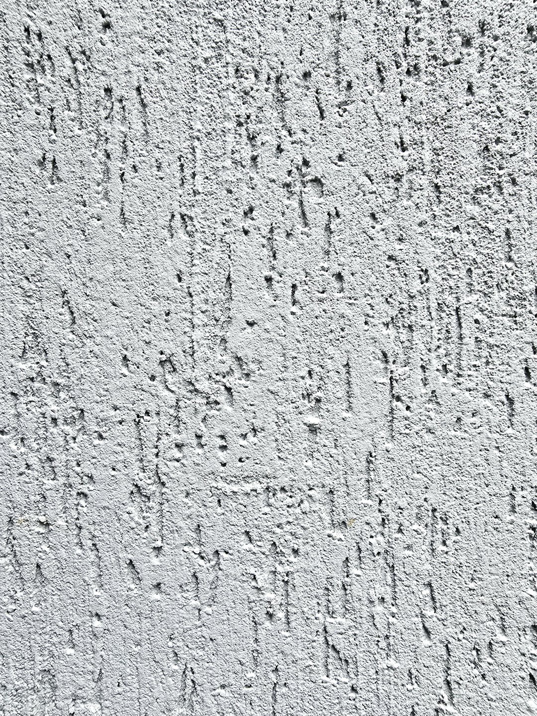 Off-white pleistermuur met een onregelmatig oppervlak en groeven.